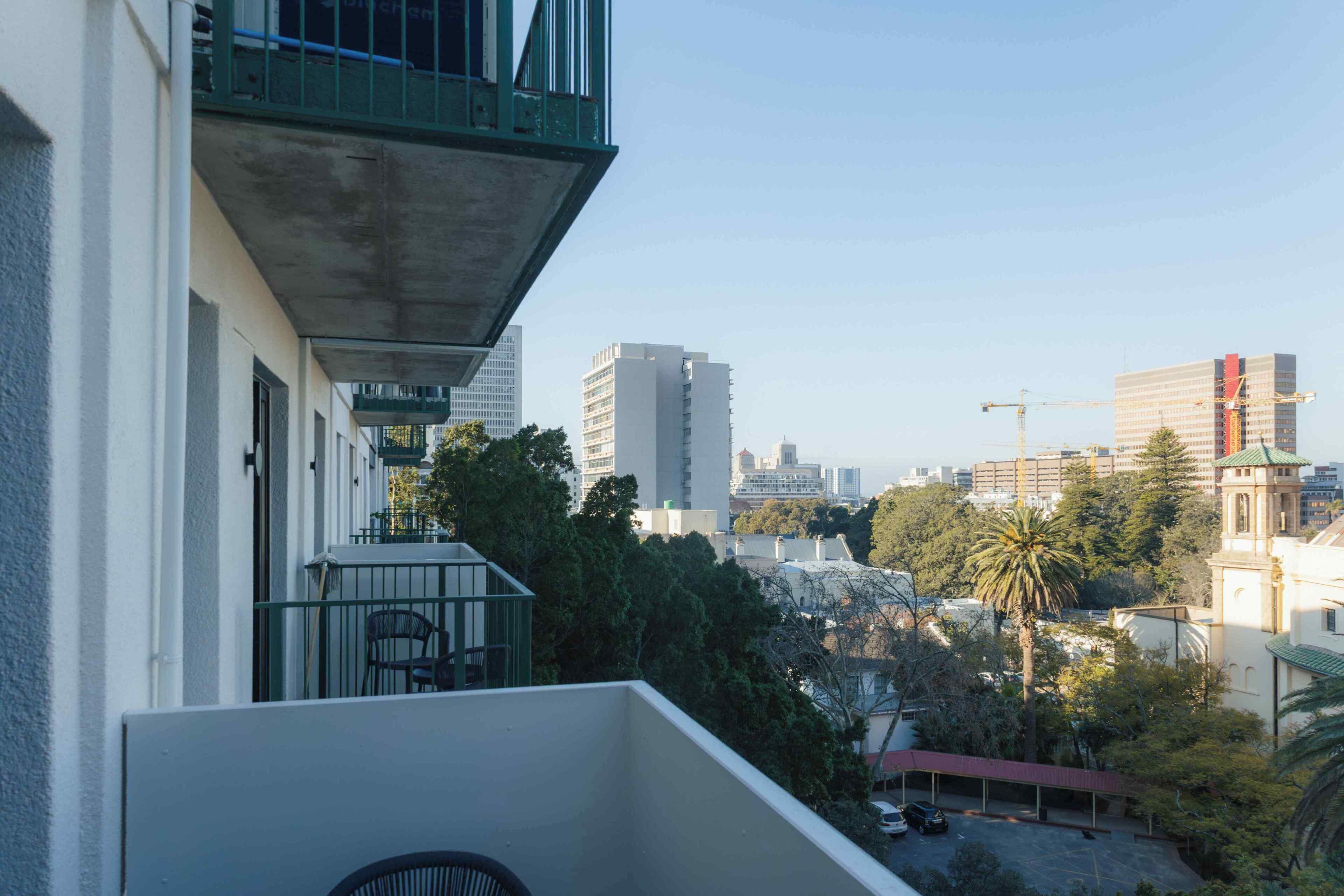 A balcony with a view of a cityscape, including tall buildings and a construction crane.