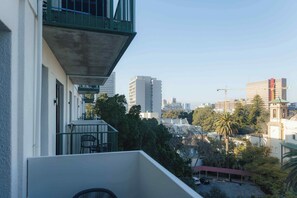 A balcony with a view of a cityscape, including tall buildings and a construction crane. - TEN on V - Fluent Serviced Apartments (Cape Town)