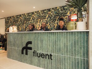 Una recepción con un logotipo, un papel tapiz estampado y una planta en maceta.