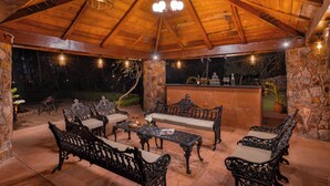 Une terrasse extérieure avec des meubles en bois, des murs en pierre et un espace bar.