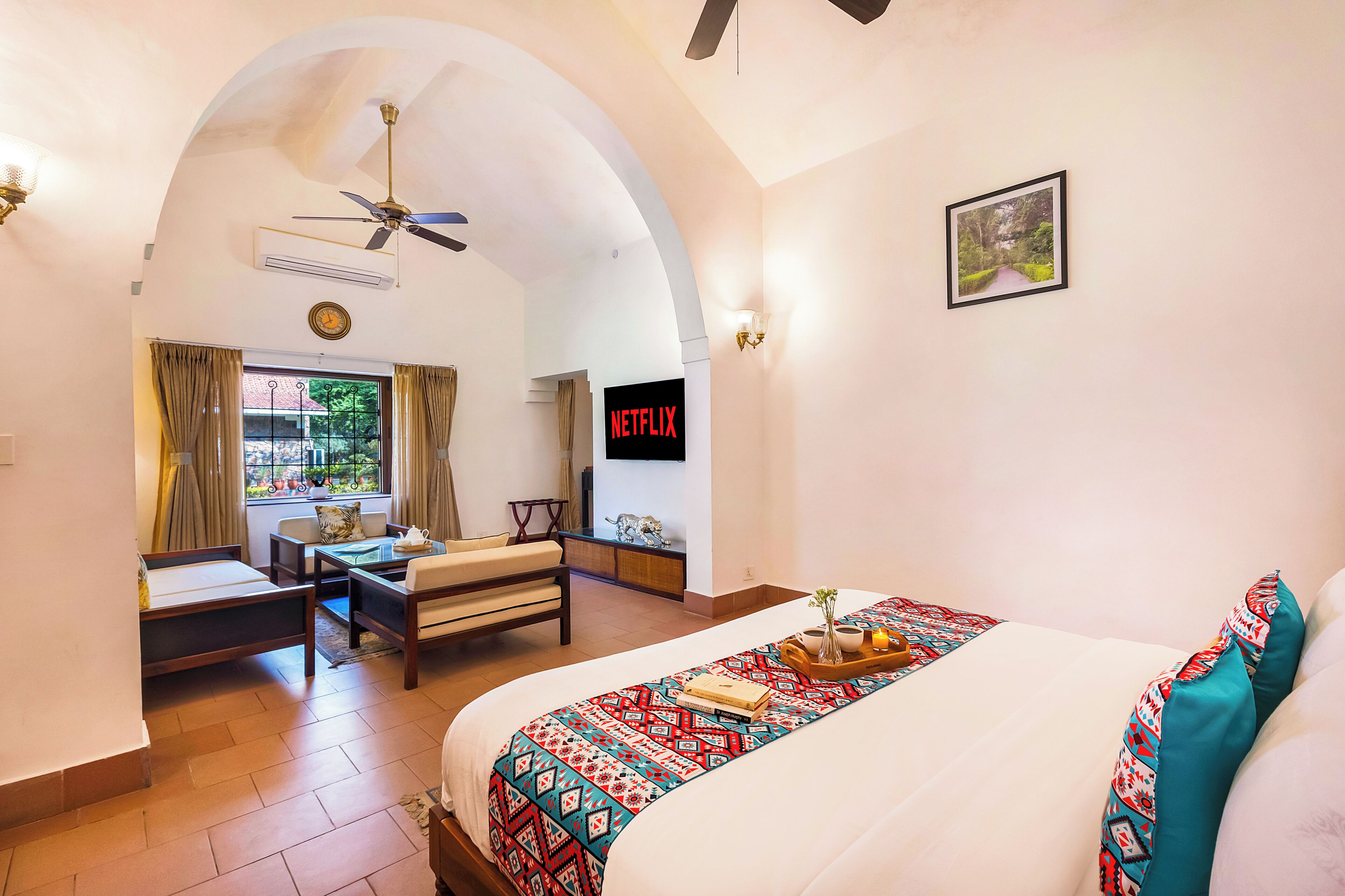 Habitación de hotel con cama, escritorio, silla, televisor y vistas al exterior.