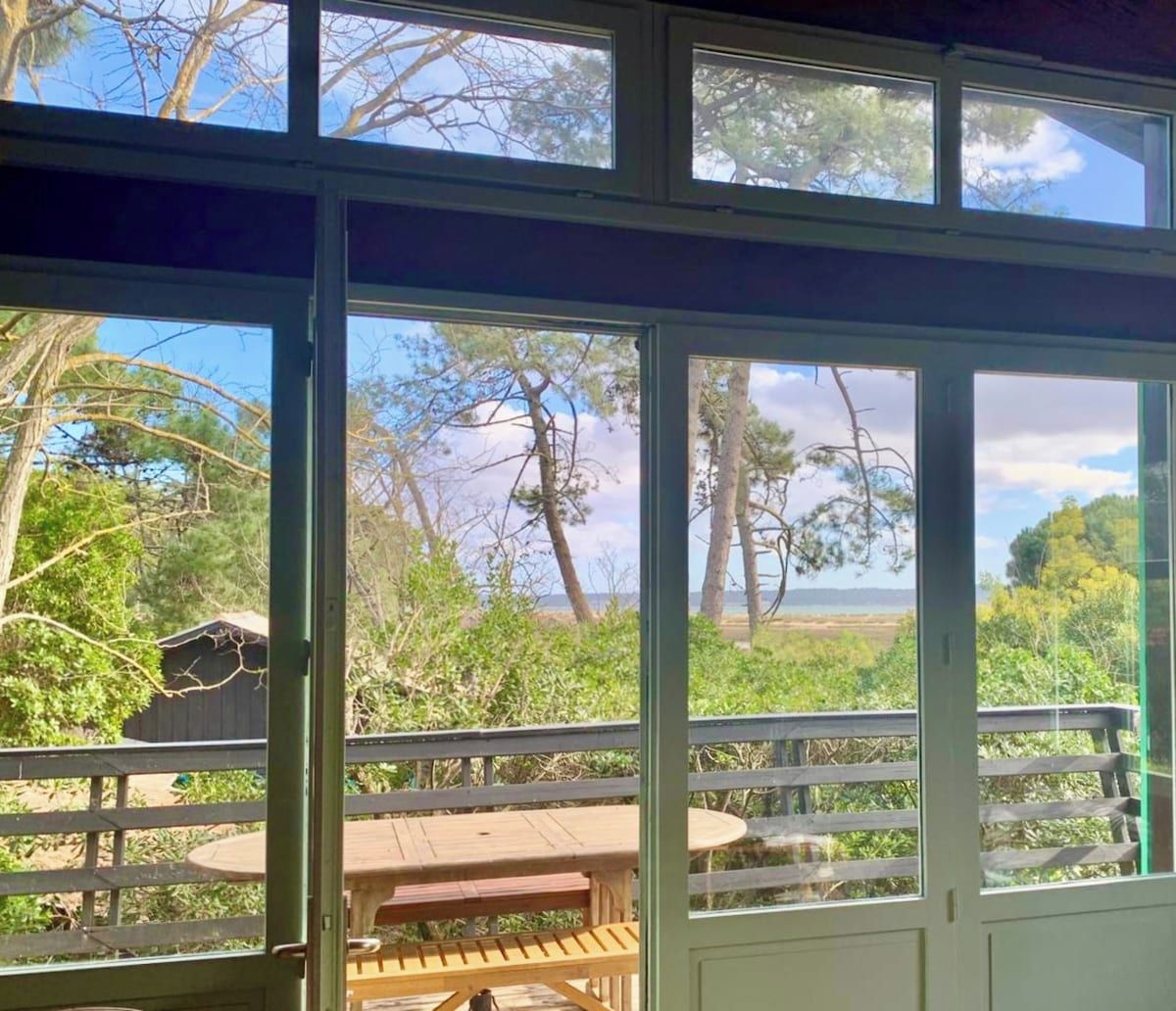 A room with a large window overlooking a deck with a table and chairs.