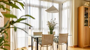A dining area with a glass table, wicker chairs, a hanging light, and a wooden cabinet. - Isla de Cuba 2K Apartment – Colombres (Colombres)