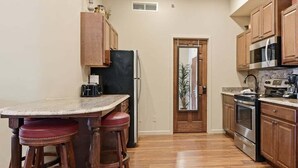 A compact kitchen with wooden cabinets, a refrigerator, a microwave, and a stove. - 391 Edgewater | Downtown Charlevoix | Pool, Hot Tub, Sauna | Full Kitchen (Charlevoix)