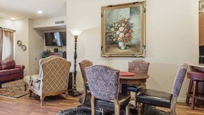 A living room with a sofa, armchairs, a dining table with chairs, a TV, and a painting. - 391 Edgewater | Downtown Charlevoix | Pool, Hot Tub, Sauna | Full Kitchen (Charlevoix)