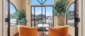 A room with two orange chairs, a small table, and a view of a parking area through a large window. - 391 Edgewater | Downtown Charlevoix | Pool, Hot Tub, Sauna | Full Kitchen (Charlevoix)