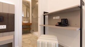 Un baño moderno con ducha, lavabo y una cafetera sobre una repisa.