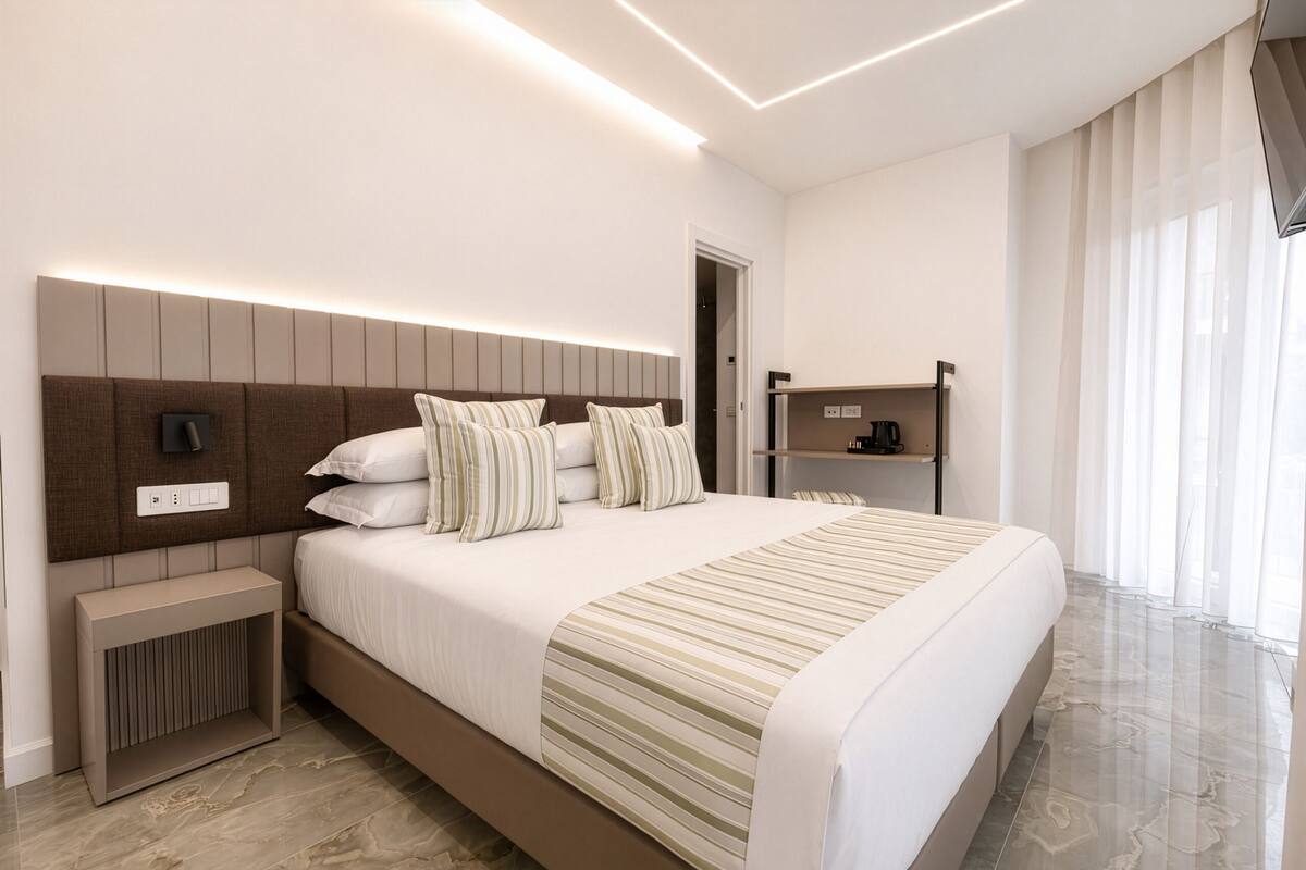 Une chambre d’hôtel moderne dotée d’un grand lit, de tables de chevet, d’une étagère intégrée et offrant une vue sur la ville.