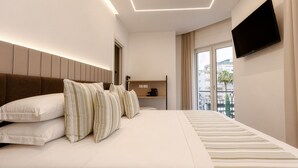 Habitación de hotel moderna con una cama grande, un televisor de pantalla plana, una mesita de café pequeña y vistas a la ciudad.