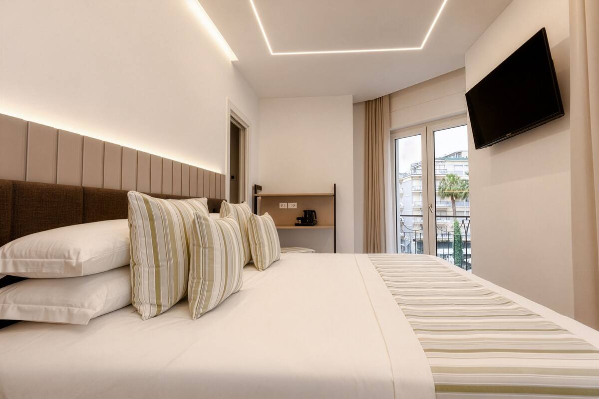 Une chambre d’hôtel moderne dotée d’un grand lit, d’un téléviseur à écran plat, d’une petite table basse et offrant une vue sur la ville.