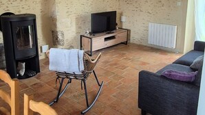 A living room with a fireplace, a TV, a sofa, and a dining area with chairs. - Country house (Vivoin)