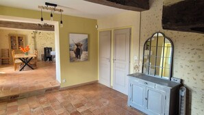 A room with a tiled floor, a wooden dining table with chairs, a cabinet with a mirror, and a door. - Country house (Vivoin)