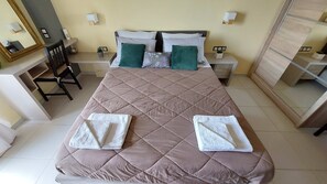 Ein ordentlich gemachtes Bett mit gestepptem Kopfteil, zwei Kissen und zwei gefalteten Handtüchern.