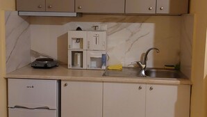 A compact kitchen with a built-in dishwasher, a coffee machine, and a sink with a faucet. - Tsiamis Sea Sun - Cozy and Stylish Nest (Corinth)