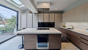 A modern kitchen with a central island, built-in appliances, and a large window. - 2 Private Ensuite Rooms Shared With Friendly Host (London)