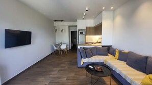 Uma sala de estar moderna com um sofá, uma mesa de centro e uma TV fixada na parede.