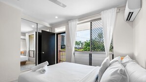 Une chambre d’hôtel moderne avec un grand lit, une porte coulissante donnant sur un balcon et une vue sur la ville.