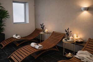 Et spa-rum med træbænke, et vindue og vægmonterede stearinlys.