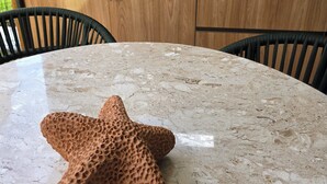Une cuisine dotée d’un plan de travail en marbre, de meubles en bois, d’une plante suspendue et d’une décoration en forme d’étoile de mer.