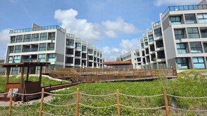 Un bâtiment moderne à plusieurs étages, doté de grandes fenêtres et d’un pont en bois reliant les différentes sections.