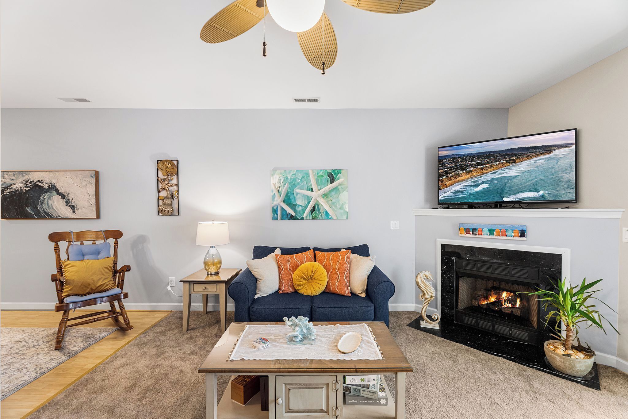 Un salon comprenant un canapé, un téléviseur, une cheminée et un ventilateur de plafond.