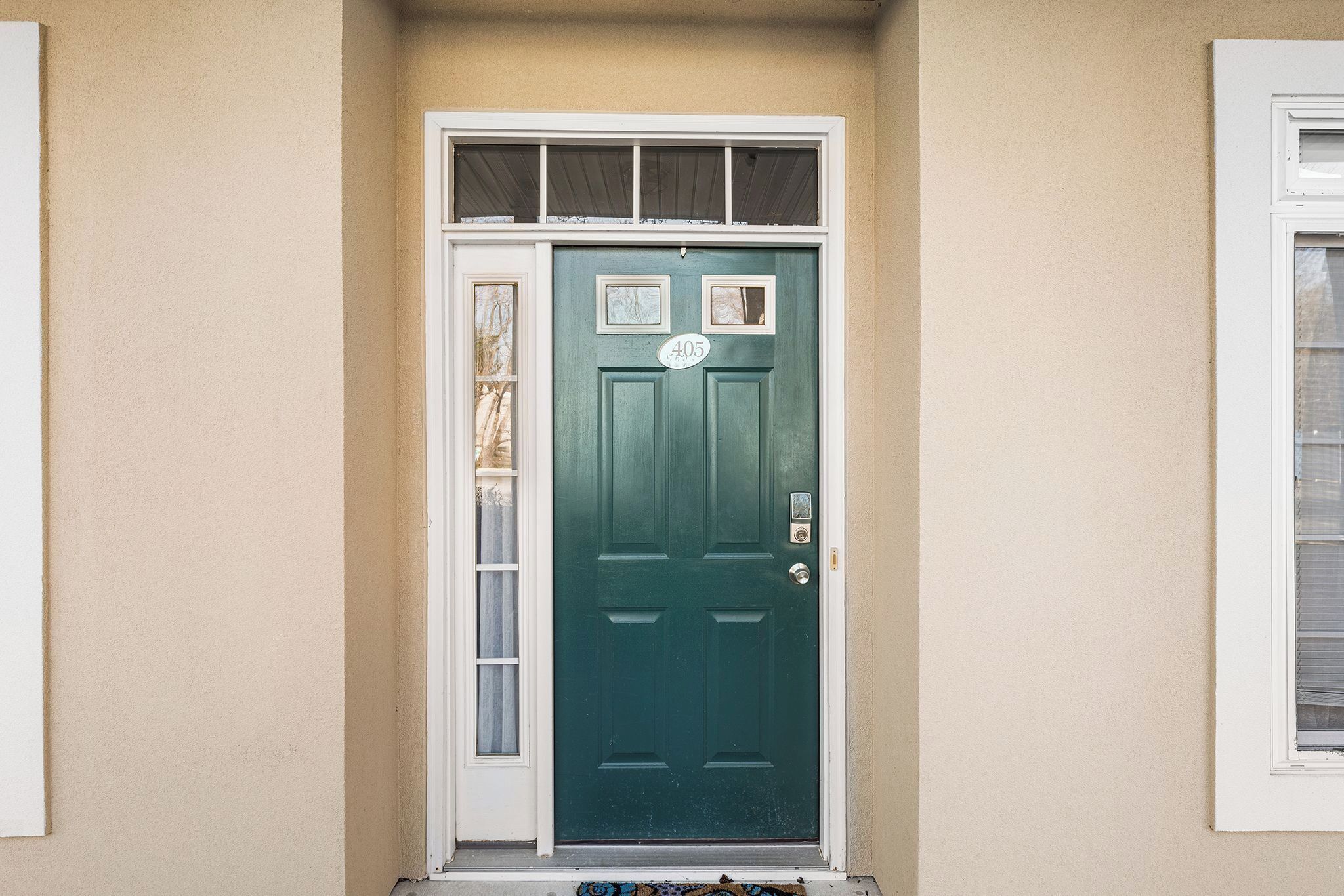 A green door with a number plate, a window above it, and a small step leading to the door.