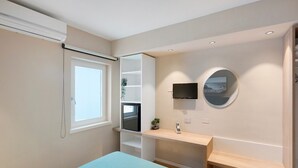 Une chambre à coucher avec un lit, un bureau, une télévision et une fenêtre.
