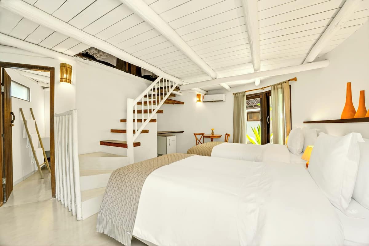 A bedroom with a large bed, a staircase, a desk, and a chair.