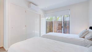 A bedroom with two beds, a sliding glass door, and an air conditioning unit. - Mission on Mission~ Overlooking the town (Mission Beach)