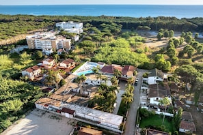 Una vista aerea di una zona residenziale costiera con edifici, una piscina e una spiaggia.