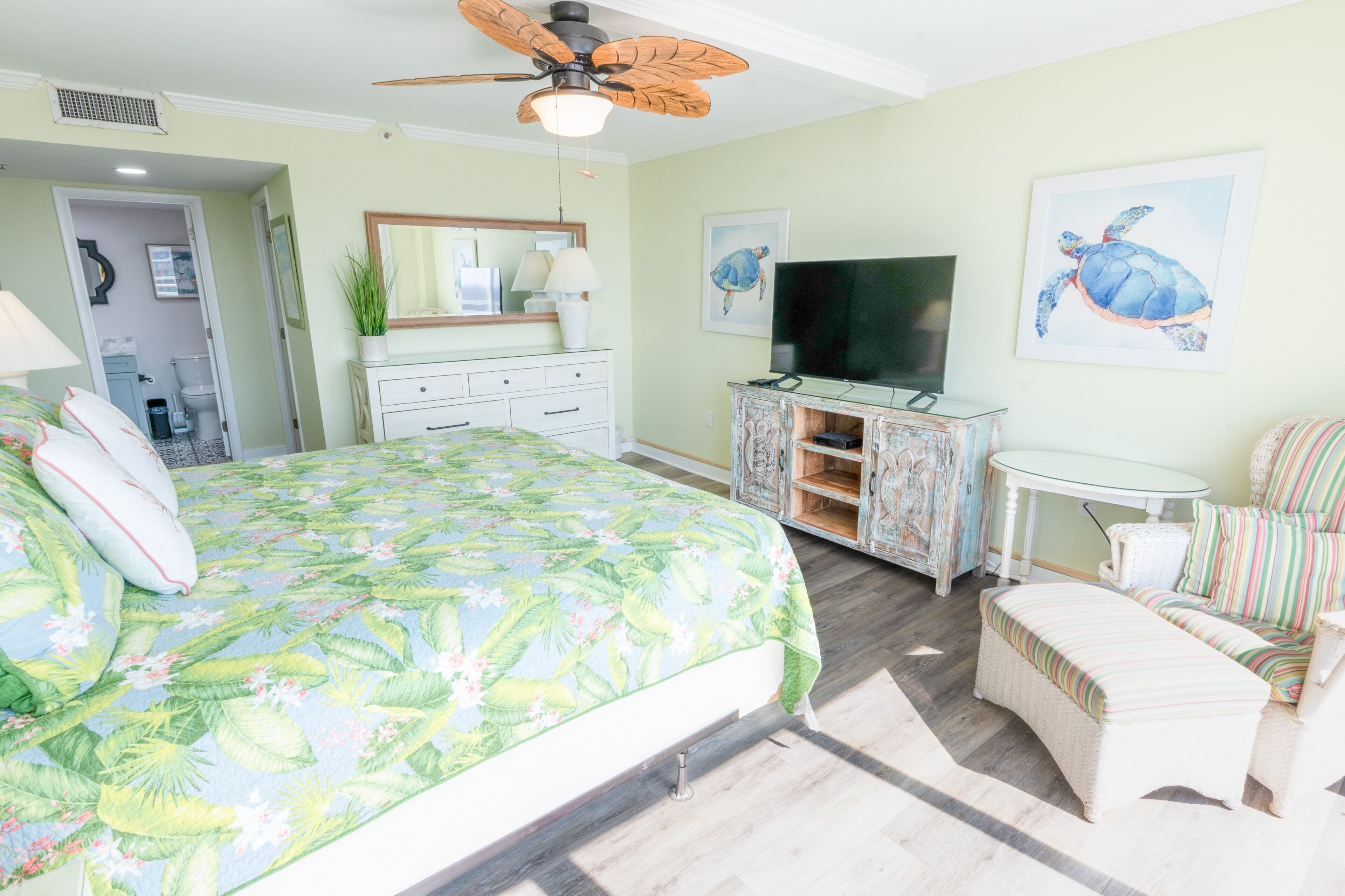 A bedroom with a bed, a television, a chair, and artwork on the walls.