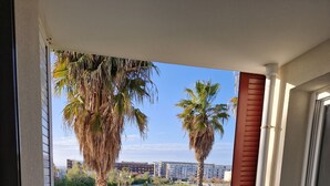 Un balcone con tavolo e sedie, vista sulla città e palme.
