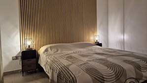 Una camera da letto con un letto, due comodini, una parete con listelli di legno verticali e un tavolino con una lampada.