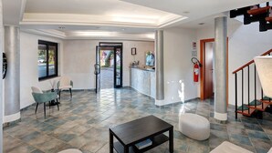 A hotel lobby with a reception desk, seating area, and a staircase. - Marina Living Rooms – Economy Double Room with Shared Pool, Wi-Fi & Air Conditioning (Laura)