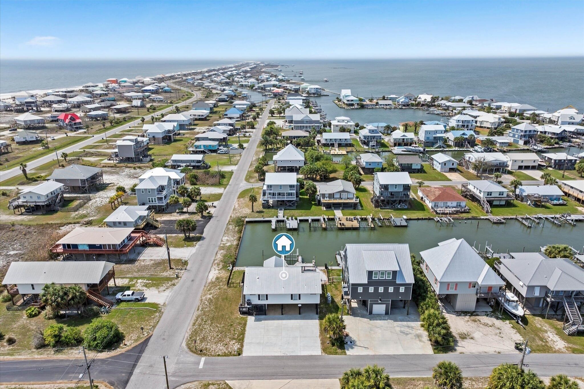 A coastal residential area with houses, a marina, and a clear view of the ocean.
