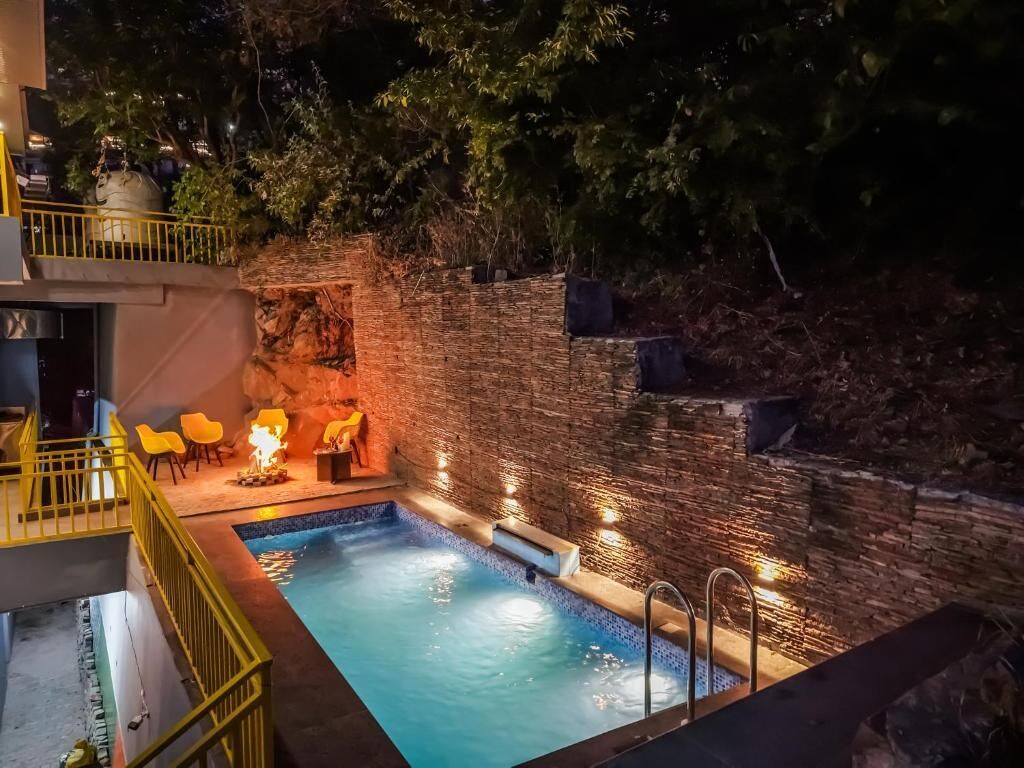 A swimming pool with a stone wall and a small fire feature.