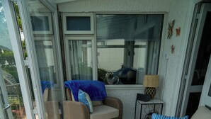 Ein sonnendurchflutetes Zimmer mit Glastür, Korbmöbeln, einem gewebten Couchtisch und einer Lampe.