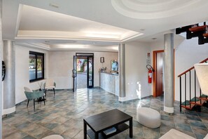 Un hall d’hôtel comprenant un comptoir d’accueil, un espace salon et un escalier.