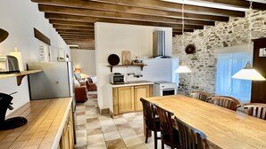 Une cuisine moderne avec un plan de travail en bois, une table à manger avec des chaises et un mur en pierre.