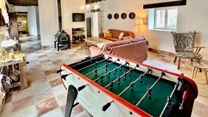 Une pièce avec une table de baby-foot, un canapé, un fauteuil et une fenêtre.