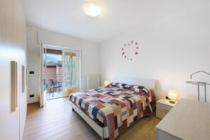 A bedroom with a bed, bedside tables, a nightstand, a window, and a view of the outside. - Casa San Rocco Marniga (Brenzone sul Garda)