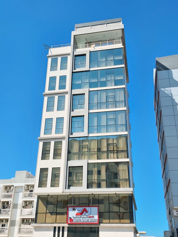Un edificio de hotel de varios pisos con un letrero llamativo que dice 'EA Hotel Apartments'.