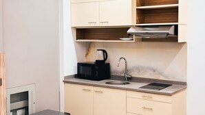 Kompakti keittiö, jossa on sisäänrakennettu mikroaaltouuni, pesuallas ja kahvinkeitin.