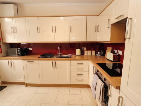 A kitchen with white cabinets, a black microwave, a sink, and a toaster.