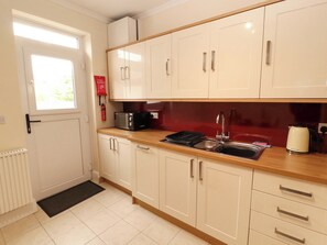 Una cocina con gabinetes blancos, un tostador negro, un lavabo y una tetera.