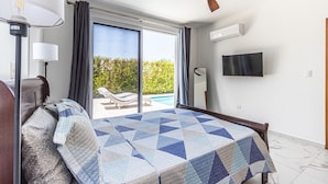 A bedroom with a bed, a ceiling fan, a TV, and a view of a pool. - Family Villa With Private Pool in Sosua Ocean Village (Sosúa)