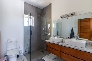 A modern bathroom with a glass shower enclosure, two sinks, a large mirror, and a wooden vanity. - Luxurious Villa With Private Pool in Sosua (Sosúa)