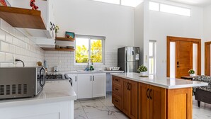 A modern kitchen with white cabinets, a wooden island, a stainless steel refrigerator, and a window with a view of greenery. - Family Villa With Private Pool in Sosua Ocean Village (Sosúa)