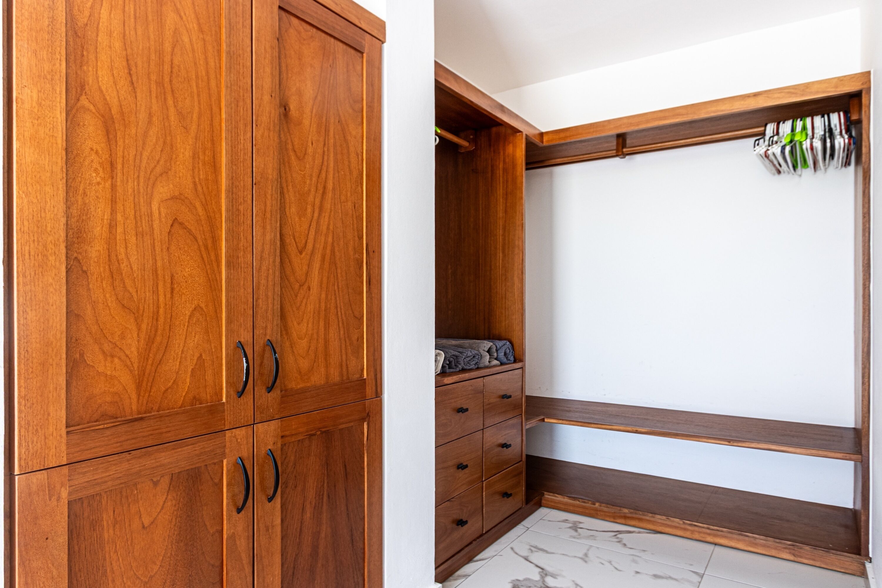 A wooden wardrobe with multiple compartments and drawers.