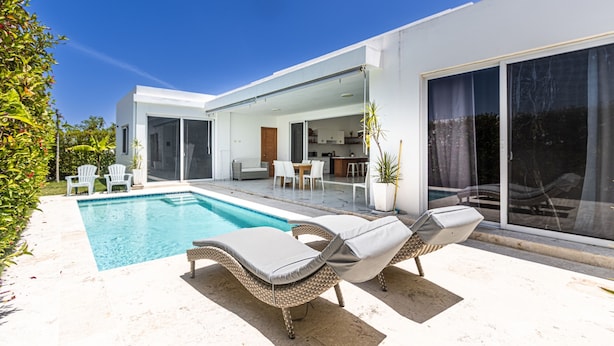 A modern house with a swimming pool, outdoor seating, and large sliding glass doors. - Family Villa With Private Pool in Sosua Ocean Village (Sosúa)